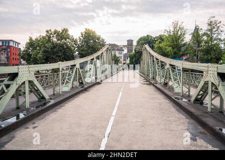 Schmale Stahlstraßenbrücke, die an einem bewölkten Sommertag von einem alten Hafengebiet in ein Wohnviertel führt Stockfoto