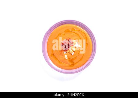 Runder Teller mit Salmorejo auf weißem Hintergrund, begleitet von Ei und Schinken. Stockfoto