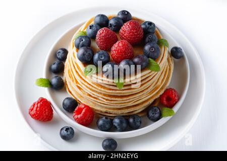 Stapel köstlicher Pfannkuchen mit Beeren und Minzblatt Stockfoto