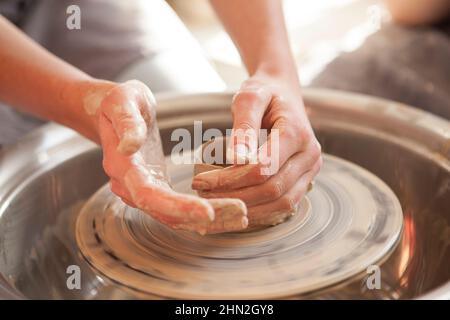 Nahaufnahme der Hände einer nicht erkennbaren Frau, die Ton auf dem Töpferrad formt Stockfoto