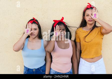 Multiethnische Gruppe von Frauen, die ihre Hände als Symbol für Krebs zeigen. Konzept von Feminismus und Geschlechtergleichstellung. Stockfoto