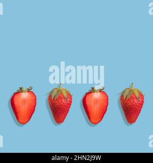 Geschnittene und ganze Erdbeere auf hellblauem Hintergrund, kreatives Flat Lay Healthy Food-Konzept, Draufsicht. Speicherplatz kopieren Stockfoto