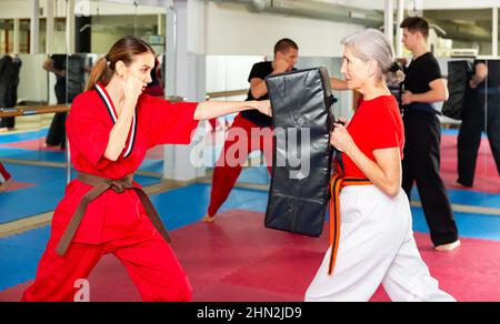 Junge Frau im roten Kimono, die Schläge auf den Schlagschutz abgibt Stockfoto