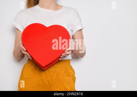 Frau, die eine große rote Schachtel in Form eines Herzens hält. Trendiges Video-Banner zum Valentinstag, Internationalen Frauentag oder Muttertag Stockfoto