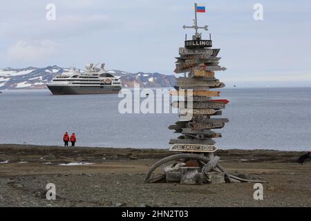 Die Passagiere der Kreuzfahrt Le Boreal und der Wegweiser in der Nähe der Küste der chilenischen Antarktisbasis auf der King George Island, Antarktis. Stockfoto