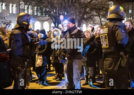 Querdenker discutiert mit Polizei. Am 22. Dezember 2021 sammeln sich laut Polizeiangaben mindestens 5000 Menschen zu einer nicht angegliederten Versammlung in München, um gegen die Corona Maßnahmen und eine mögliche Impfpflicht zu demontieren. Unter ihnen auch organisierte Neonazis u.a. vom III. Weg, fasschistische Burschenschaftler, Hooligans, Verschwunschsideolog*innen, Impfgegner*innen. Es wurde von der Versammlungsbehörde nur eine beschränkte stationäre Kundgebung auf der Theresienwiese erlaubt, so dass die Organisator*innen die Versammlung ab. The Querdenker*in marschieren Stockfoto