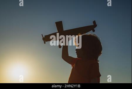 Kinderträume. Junge Pilot mit Spielzeug Flugzeug, Silhouette. Kinder spielen im Freien. Frohe Kindheit. Tagträumen. Stockfoto