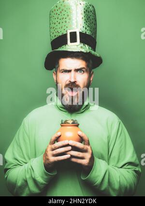 Bärtiger Mann mit Kobold-Kostüm isoliert auf grünem Hintergrund. Bärtiger Mann, der den St. Patrick's Day feiert. Kobold Mann in grünen Hut und Stockfoto