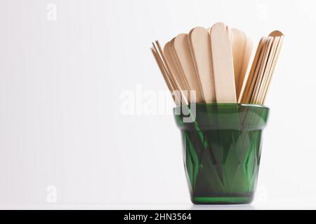 Holzspachtel. Wachsspatel zur Enthaarung. Shugaring mit Zuckerpaste. Haarentfernung mit Zucker. Holzspatel in einem Glas. Stockfoto