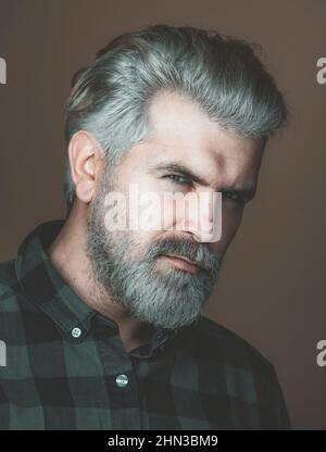 Reifer blonder bärtiger Kerl mit trendiger Frisur im lässigen Hemd lächelnd und in der Kamera schauend. Nahaufnahme eines sehr schönen Mannes. Stockfoto