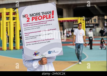 Hongkong, China. 12th. Februar 2022. Ein Mitarbeiter des Arbeitsministeriums hält ein Schild, das ausländische inländische Helfer über die sozialen Distanzierungsregeln COVID-19 warnt. Angesichts der jüngsten Zunahme der Fälle in Hongkong hat die Regierung die Tests erhöht und die Grenzen für soziale Zusammenkünfte erhöht, um die Krankheit zu bekämpfen. Kredit: SOPA Images Limited/Alamy Live Nachrichten Stockfoto