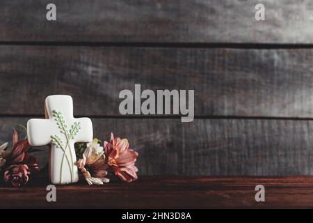 Ostern Urlaub konzeptionellen Hintergrund auf rustikalen Holzbrettern. Foto von weißem Lebkuchenkekse Kreuz Form, Blumen Blumenstrauß auf der Tischplatte. Karte mit Platz zum Platzieren von Text. Minimalkonzept Stockfoto