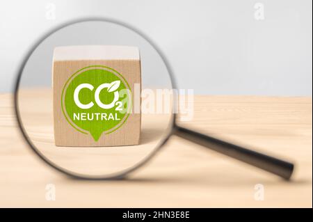 CO2 Neutral. CO2 Neutralzeichen durch Vergrößerungsglas auf Holztisch. CO2 Neutrales Engagement in Wirtschaft, Finanzen und Industrie zur Reduzierung von CO2-Diox Stockfoto