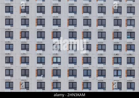 Fragment der Wand eines mehrstöckigen weißen Gebäudes mit Fenstern. Stockfoto