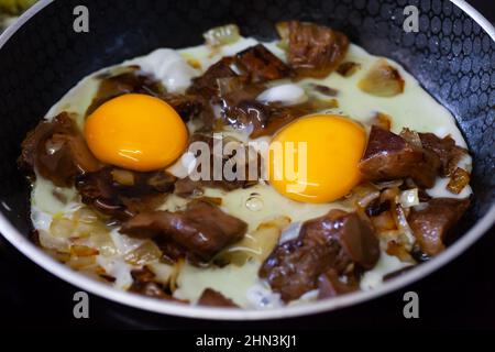 Spiegeleier mit roten Pinienpilzen in der Pfanne Stockfoto