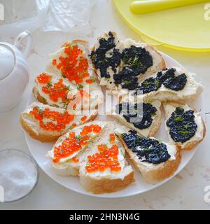 Sandwiches mit rotem und schwarzem Kaviar auf einem Teller auf dem Tisch Stockfoto