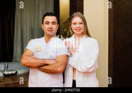 Schöner lächelnder Kunde, der sich mit einem männlichen Massagemeister zufrieden fühlt Stockfoto