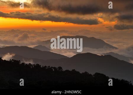 Costa Rica Sonnenuntergangslandschaft. Hügel von Tapantí nationl Park Nebelwald, Costa Rica. Tropische Berge mit weißen Sturmwolken. Regnerischer Tag im Vordergrund Stockfoto