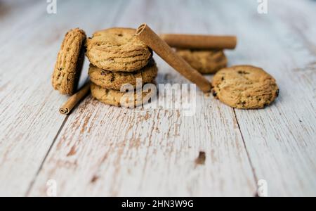 Stapel Haferflocken und Zimtstangen auf einem Holztisch. Lecker und Junk-Food-Konzept. Vorderansicht. Stockfoto