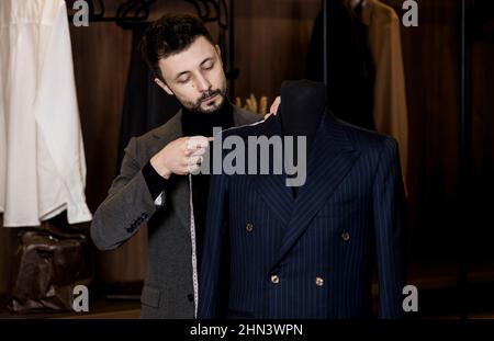 Junge Schneiderin in der Werkstatt. Modedesignerin nimmt Messungen von einer Schaufensterpuppe Stockfoto