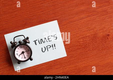 Draufsicht Bild von schwarzem Wecker und blauem Papier mit Text TIME'S UP. Platz für Text kopieren Stockfoto