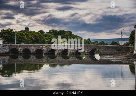 Alte Bogenbrücke über den Vartry River, Wicklow Stadt. Typisch irische Straße auf einer historischen Steinbrücke über ruhiges Wasser in einem ländlichen Dorf Stockfoto