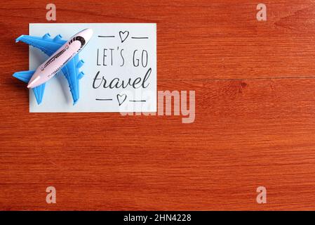 Draufsicht Bild von Spielzeug Flugzeug und blauem Papier mit Text LET'S GO TRAVEL. Platz für Text kopieren Stockfoto