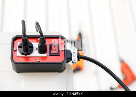 Nahaufnahme der roten Steckdosen 2 des Anhängersteckers mit ein-/Ausschalter für die Verwendung mit Handwerkzeugen. Stockfoto