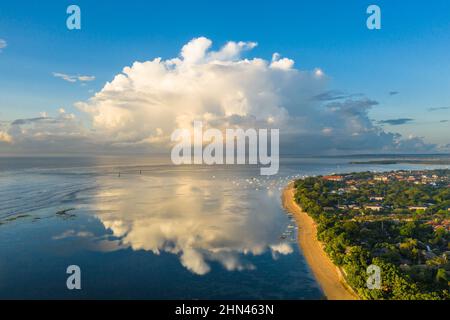 Dramatische Luftaufnahme des Sonnenaufgangs über dem Strand von Sanur mit einer massiven Wolke in Bali, Indonesien Stockfoto