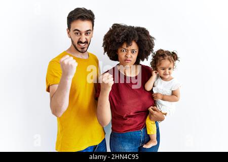 Junge Familie aus schwarzer Mutter und hispanischer Vater mit Tochter, die wütend und wütend die Faust ragte, frustriert und wütend, während sie vor Wut schrie Stockfoto