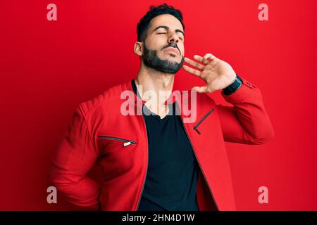 Junger hispanischer Mann mit roter Lederjacke, der an Nackenschmerzen, Handberücken des Halses und Muskelschmerzen leidet Stockfoto