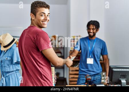 Zwei Männer, Ladenbesitzer und Kunde, die im Bekleidungsgeschäft mit Dollars einkaufen Stockfoto