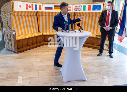 14. Februar 2022, Mecklenburg-Vorpommern, Schwerin: Bundesminister für Wirtschaft und Klimaschutz, Robert Habeck (Bündnis 90/die Grünen), beantwortet neben Reinhard Meyer (SPD, r), Minister für Wirtschaft, Tourismus und Verkehr Mecklenburg-Vorpommerns, Während einer Pressekonferenz im Wirtschaftsministerium Mecklenburg-Vorpommerns vor einem Strandstuhl mit den Flaggen verschiedener Länder. Habeck besucht nach einem Treffen mit dem Landesabteilungsleiter Meyer die insolventen MV Shipyards Group und das Wasserstoffenergieunternehmen Apex in Rostock-Laage. Stockfoto