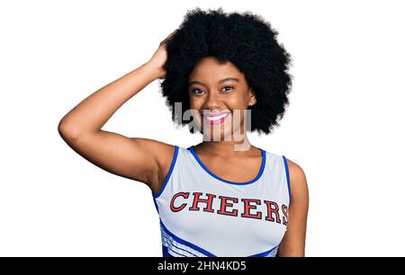 Junge afroamerikanische Frau in Cheerleader-Uniform verwirrt und wundert sich über Fragen. Unsicher mit Zweifel, mit der Hand auf dem Kopf denkend. Nachdenklich Stockfoto