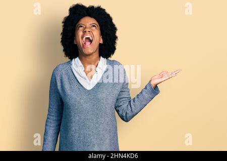 Junge afroamerikanische Frau präsentiert sich mit offenen Handflächen wütend und wütend schreiend frustriert und wütend, schreiend mit Wut aufschauend. Stockfoto