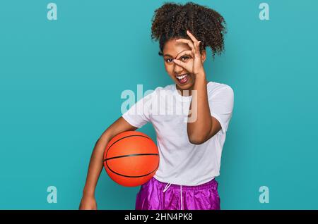 Junge afroamerikanische Mädchen spielen Baseballspiele halten Fledermaus und Ball lächelnd glücklich tun ok Zeichen mit Hand auf Auge durch die Finger schauen Stockfoto