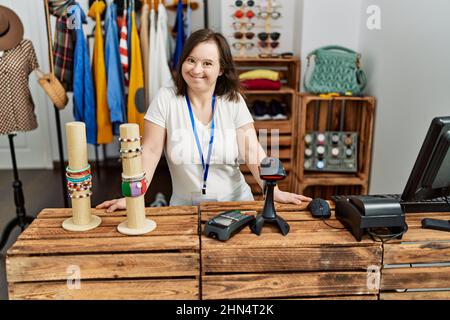 Brünette Frau mit Down-Syndrom lächelnd arbeitet als Verkäuferin im Einzelhandel Stockfoto