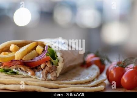 Griechisches Gyros Street Food zum Mitnehmen, schön verpackt mit Tomaten, Souvlaki, griechischem Salat, Zwiebeln und Pommes frites Stockfoto