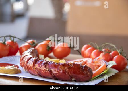 Gegrillte Würstchen, Street Food zum Mitnehmen, schön verpackt mit Tomaten, Souvlaki, griechischem Salat, Zwiebeln und Pommes frites Stockfoto