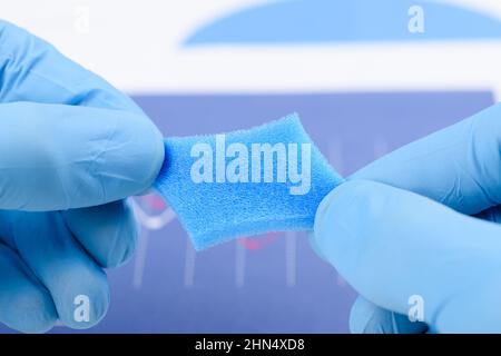 Blauer poröser Schaumstoff, der in den Händen des Wissenschaftlers im Labor gestreckt wurde. Forschung für Material mit neuem Eigenschaftskonzept. Stockfoto