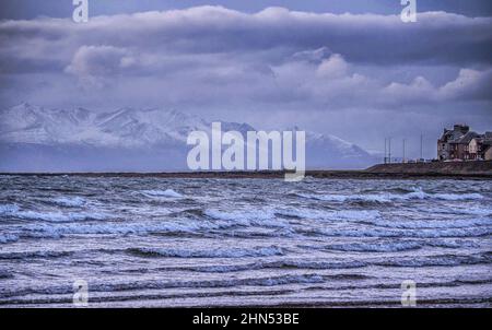 Ein Blick über den Winter auf schneebedeckte Gipfel auf der Isle of Arran vom Strand von Troon aus Stockfoto