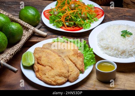 Paniertes Fischfilet, mit Reis, Salat und Zitrone Stockfoto