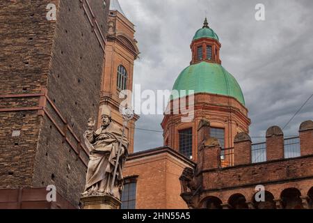 Blick auf die Statue des Heiligen Petronius, den Turm von Garisenda und die Kirche von San Bartolomeo und Gaetano bei bewölktem Himmel. Bologna, Italien. Speicherplatz kopieren. Stockfoto