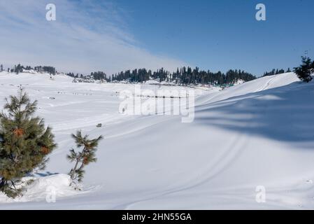 Baramulla, Indien. 12th. Februar 2022. Ein Mann geht an einem sonnigen Tag in Gulmarg auf einer schneebedeckten Piste. Gulmarg ist eine Stadt, eine Bergstation, ein beliebtes Skiziel und ein mitteiltes Gebietskomitee im Baramulla-Distrikt Jammu und Kaschmir. Die Stadt liegt in der Pir Panjal Range im westlichen Himalaya und liegt innerhalb der Grenzen des Gulmarg Wildlife Sanctuary. (Foto von Idrees Abbas/SOPA Images/Sipa USA) Quelle: SIPA USA/Alamy Live News Stockfoto