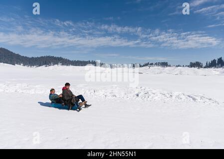 Baramulla, Indien. 12th. Februar 2022. Männer Schlittenfahrt an einem sonnigen Tag in Gulmarg. Gulmarg ist eine Stadt, eine Bergstation, ein beliebtes Skiziel und ein mitteiltes Gebietskomitee im Baramulla-Distrikt Jammu und Kaschmir. Die Stadt liegt in der Pir Panjal Range im westlichen Himalaya und liegt innerhalb der Grenzen des Gulmarg Wildlife Sanctuary. Kredit: SOPA Images Limited/Alamy Live Nachrichten Stockfoto