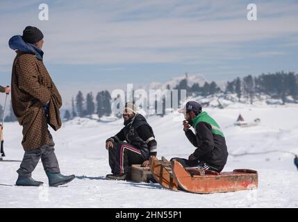 Baramulla, Indien. 12th. Februar 2022. Schlittenbesitzer sitzen auf ihren Schlitten, während sie an einem sonnigen Tag in Gulmarg auf Kunden warten. Gulmarg ist eine Stadt, eine Bergstation, ein beliebtes Skiziel und ein mitteiltes Gebietskomitee im Baramulla-Distrikt Jammu und Kaschmir. Die Stadt liegt in der Pir Panjal Range im westlichen Himalaya und liegt innerhalb der Grenzen des Gulmarg Wildlife Sanctuary. Kredit: SOPA Images Limited/Alamy Live Nachrichten Stockfoto
