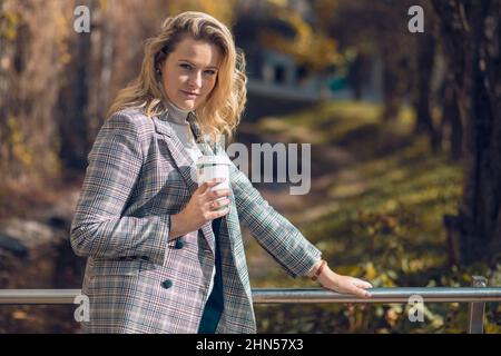 Porträt einer ziemlich ernsthaften Frau mittleren Alters in stilvoller karierter Jacke und Rollkragen-Pullover stehen auf Metallbrücke. Stockfoto