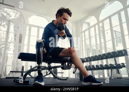 Unterschiedlich behinderter Sportler, der Bizeps im Fitnessstudio macht, um sich auf die Paralympics vorzubereiten Stockfoto