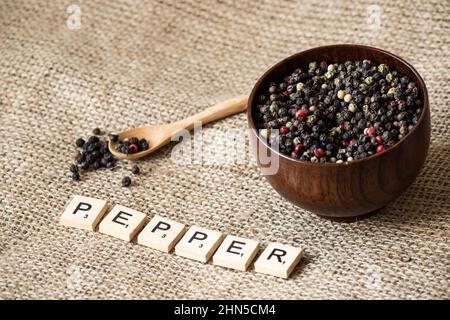 Pfefferkörner auf Holzschale auf Leinenhintergrund Stockfoto