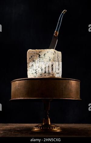 Block von blauem Schimmelkäse auf dunklem Hintergrund. Blue Cheese dunkel rustikal Food Fotografie. Stockfoto